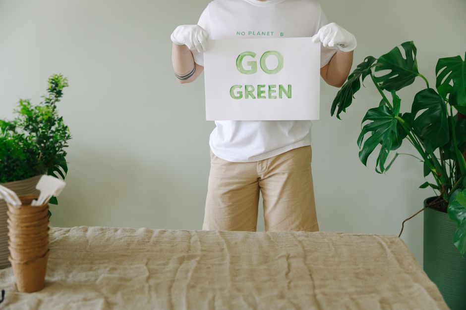 A team of three professional cleaners from End of Tenancy House Cleaning performing surface cleaning and sanitisation in a modern living room. The room features a large, L-shaped fabric sofa positione